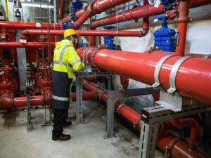 Technician inspecting industrial utility piping systems used to support commercial infrastructure