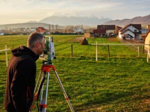 Surveyor checking an overgrown boundary corner beside an old fence and farm lane on inherited family property.